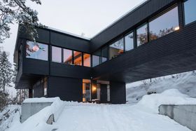 Fasaden sett i skumring med belysning i huset