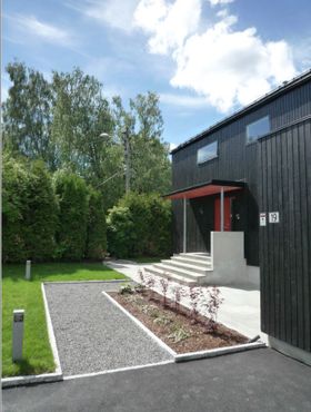 Bilde av gruslagt vei fra garasjen inn til huset. Belysning langs grusveien.