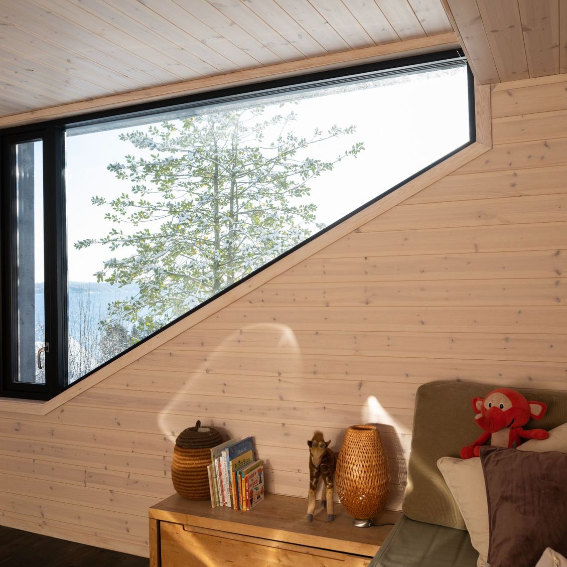 Bilde av soverom med trapes formet vindu. Panel på vegger og tak.